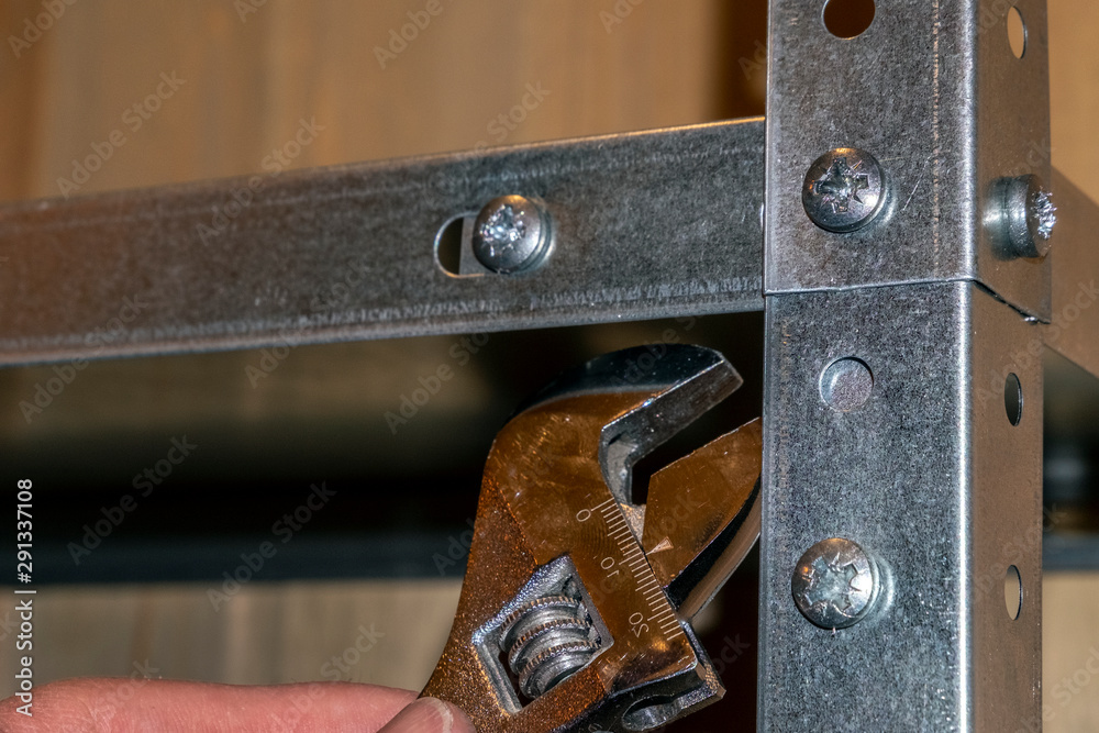 metal racks, manual labor, the use of wrench, the mechanic assembles or  disassemble the racks. hand in the frame, rear view. Stock-Foto | Adobe  Stock