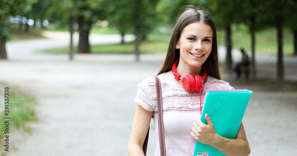 Female student holding walking outdoor in the park and smiling Female student holding walking outdoor in the park and smiling