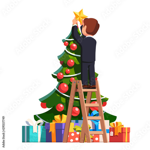Business man putting star on top of Christmas tree