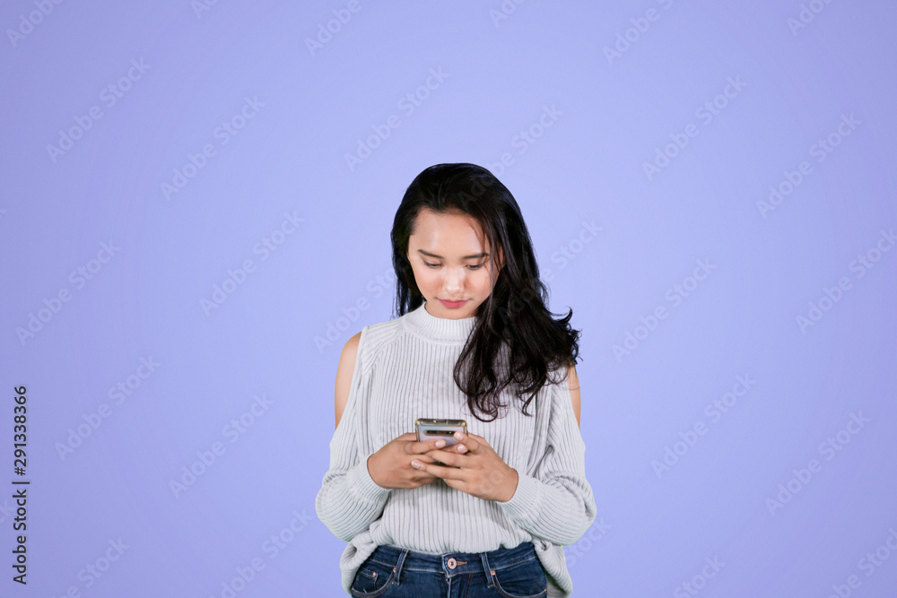 Pretty girl texting on a mobile phone in studio Pretty girl texting on a mobile phone in studio