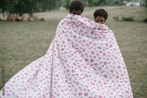 Loving couple covering theirselves by stylish sheet at nature. Strange people concept. photo