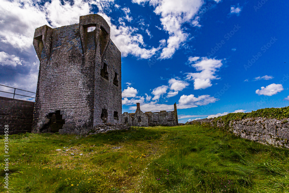 Ruined 19th century tower (A Túr Faire) in Inis Oirr Island, wonderful sunny day with a blue sky and white clouds in Inisheer, island in the west of the coast of Ireland