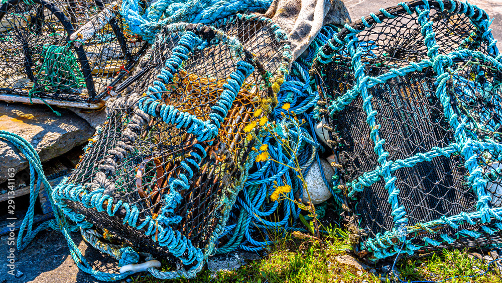 Old lobster / crab cages or fishing traps lying alongside ropes on the coast of the island of Inis Oirr, sunny day in Inisheer, an island in the west of the coast of Ireland