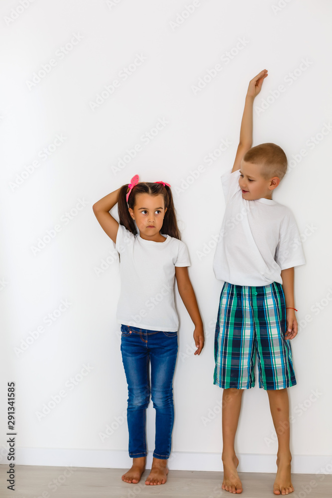 Obraz premium Little boy and girl measuring their height isolated on white background