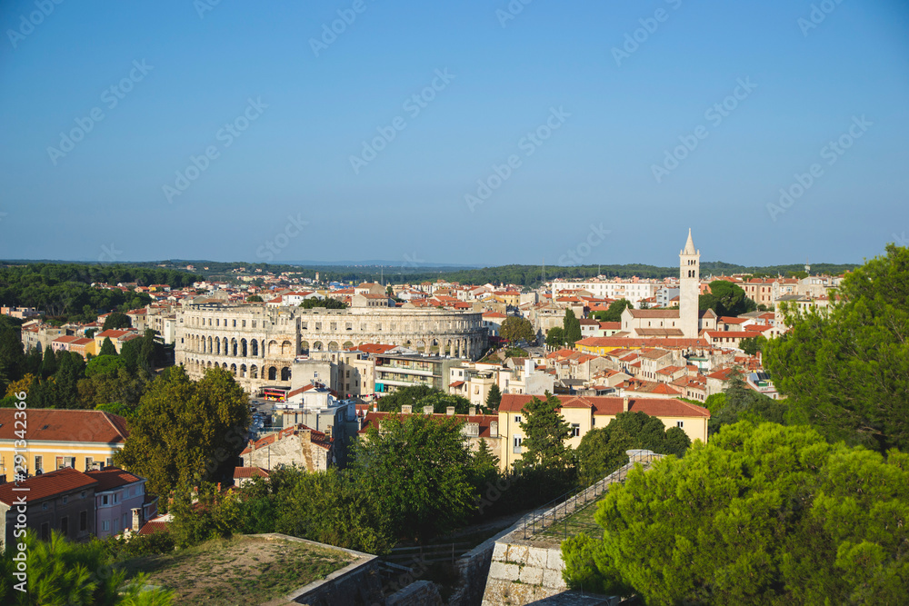Panoramic view of Pula Croatia with all buildings and green trees. Istria territory with brown roofs and mountains on the horizon. Amphitheater view, as travel postcard. Tourism wallpaper in Europe. 