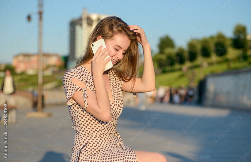 Beautiful girl in a light dress talking on the phone