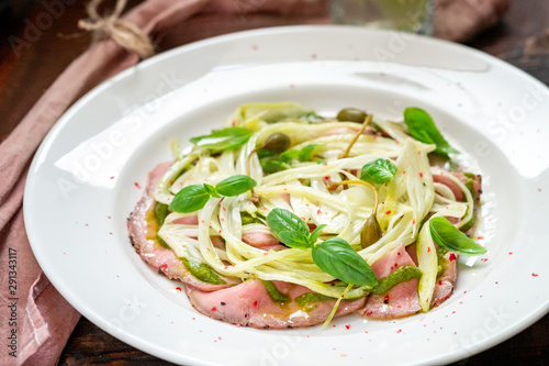 Fennel salad with beef carpaccio, Basil and pesto on a white plate. Italian gourmet snack