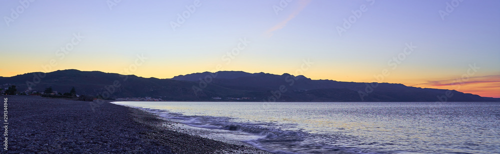 The sunset on the pebble beach with hills on the background, Kolymbari, Crete, Greece. The sunset on the pebble beach with hills on the background, Kolymbari, Crete, Greece.