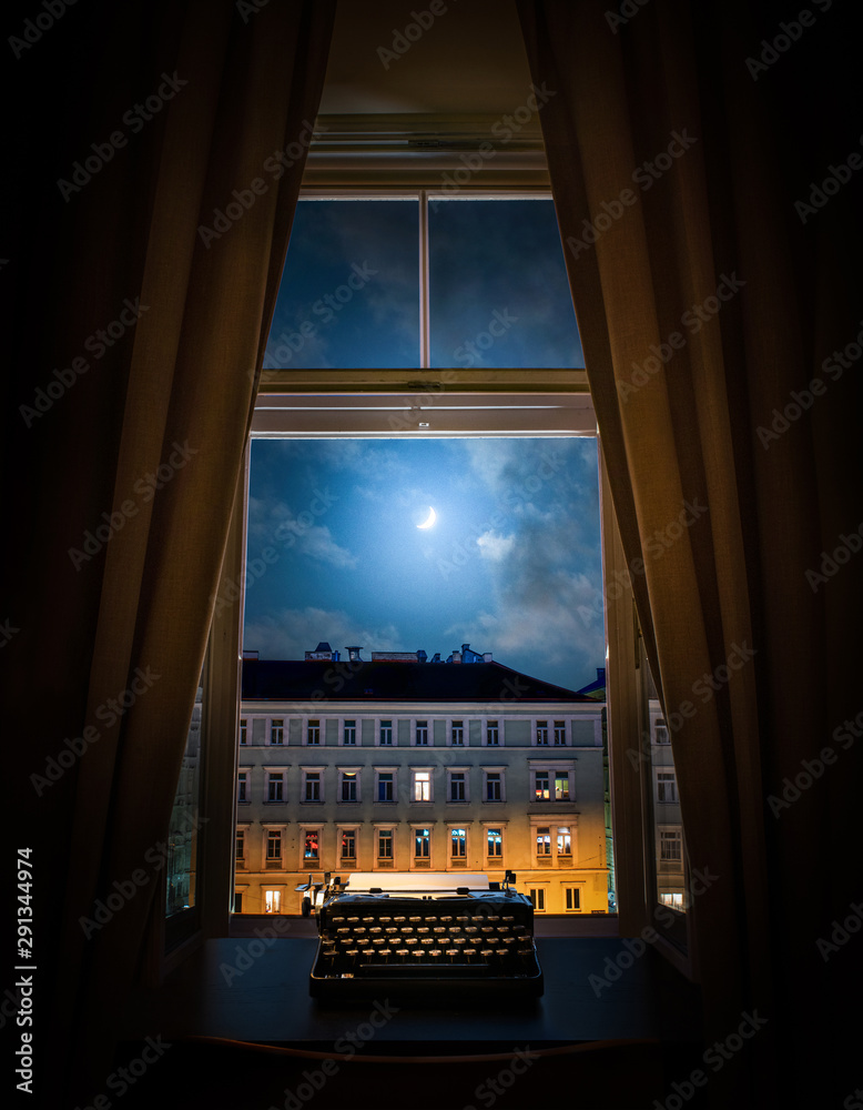 Workplace of a writer, journalist, creator. Old typewriter on the table against the background of ancient night city buildings. Retro style. The concept on scientific, historical, literature topics.