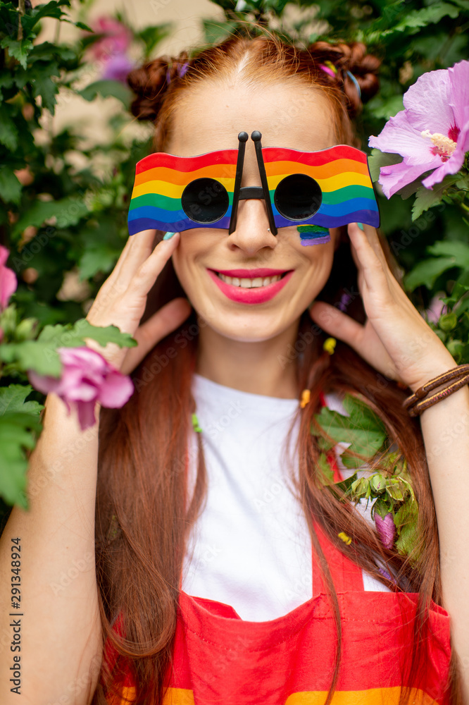 Happy lesbian with lgbt flag on her face wearing rainbow glasses and posing with smiling face Happy lesbian with lgbt flag on her face wearing rainbow glasses and posing with smiling face
