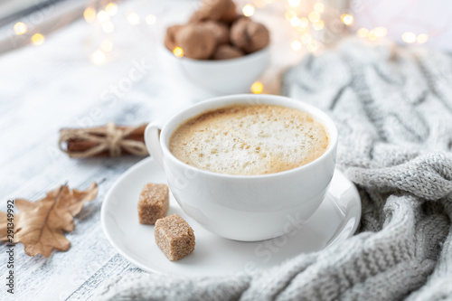 Cup of coffee, brown sugar, knitted scarf, garland. Autumn mood. Cozy autumn composition. Hygge concept. Soft focus