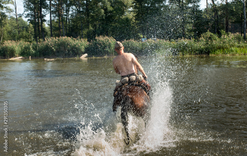 The rider on a horse crosses the shallow lake
