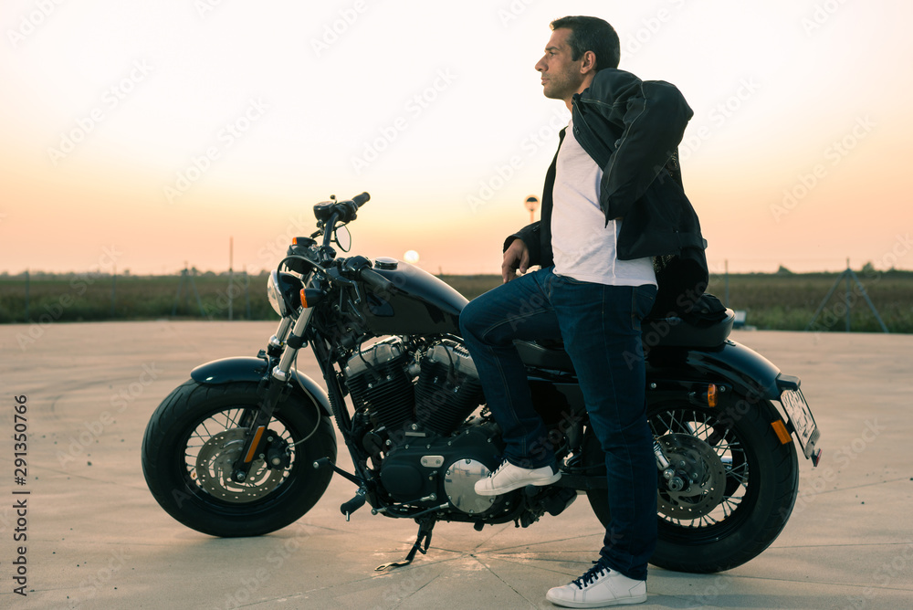 Biker man with his custom motorcycle at sunset. Biker man with his custom motorcycle at sunset.