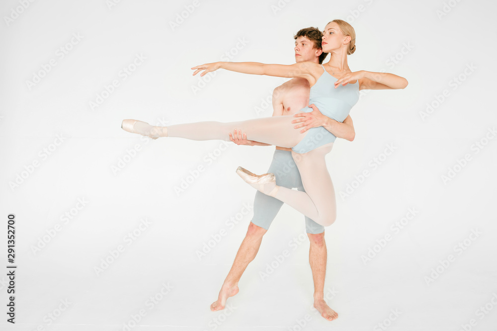 Young couple of modern ballet dancers posing over white studio background Young couple of modern ballet dancers posing over white studio background