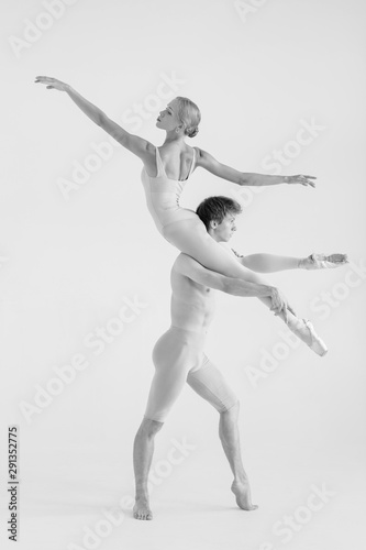 Young couple of modern ballet dancers posing over white studio background