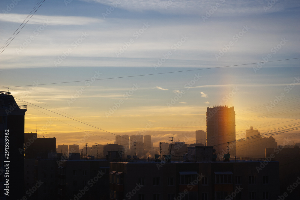 Dense urban development, buildings, city at sunrise and dawn. Sun flare. Smog and fog over the city.