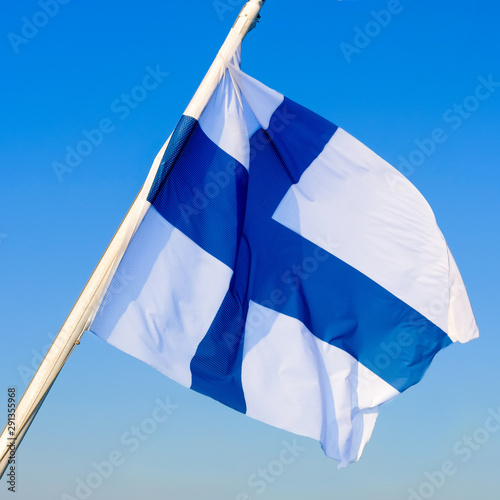 National flag of Finland fluttering on the wind against clear blue sky. Finnish flag on flagpole 