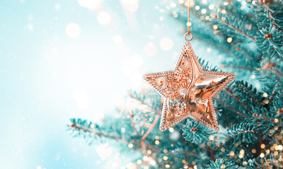 Christmas fir tree branches with golden star decoration  on blurred blue background. Christmas and Winter concept.
