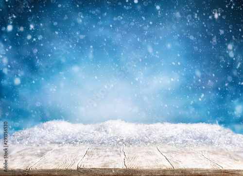 Beautiful winter background with wooden old desk and blurred blue sky. Winter, New Year and Christmas concept with snowy background.