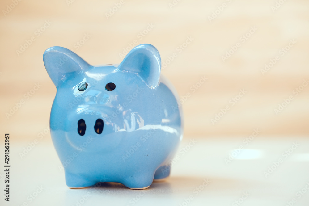 Close up of blue piggy bank standing on wooden background with copy space. Close up of blue piggy bank standing on wooden background with copy space.