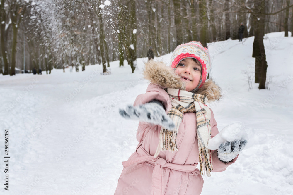A small child in the park plays snowballs in winter. Golden hour, active lifestyle. A small child in the park plays snowballs in winter. Golden hour, active lifestyle.