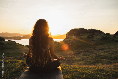 Leinwand Poster Woman meditating yoga alone at sunrise mountains