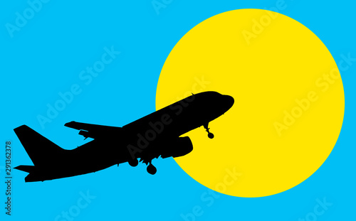 Silhouette of the plane in the blue sky against the background of the yellow sun.