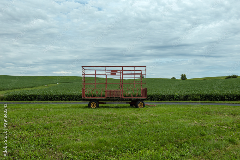 Fototapeta premium Large hay bale trailer sitting empty in vast field waiting to be used for harvest