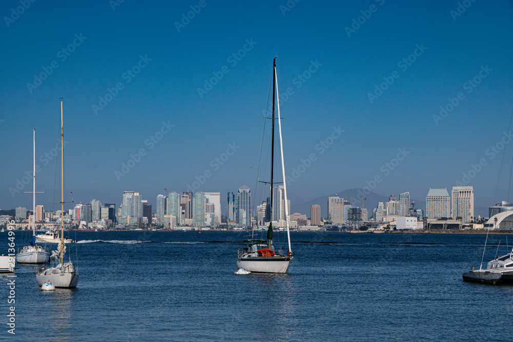 Sailboats docked off shore in San Diego bay with San Diego skyline.  Shot from Shelter Island, San Diego.  August 29, 2019