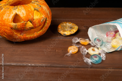 Happy Halloween pumpkin and candies. Trick or treat on a wooden table on a background of old wooden boards.