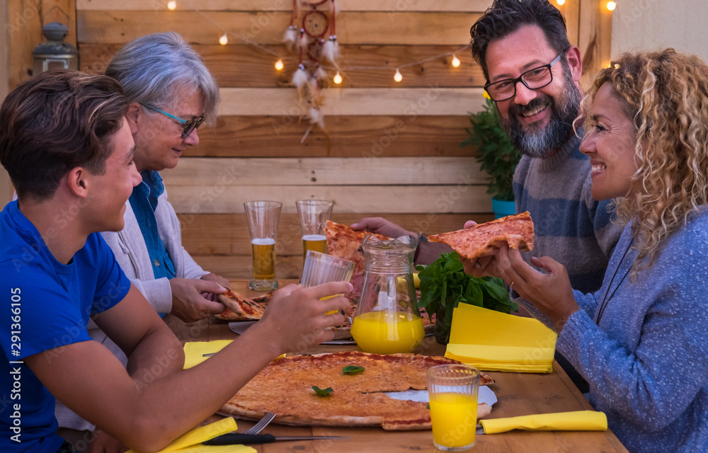 Four beautiful people share together a big pizza.  Parents with teenager son and grandmother. Wooden table and background Multi generation family. Concept of happiness and love.