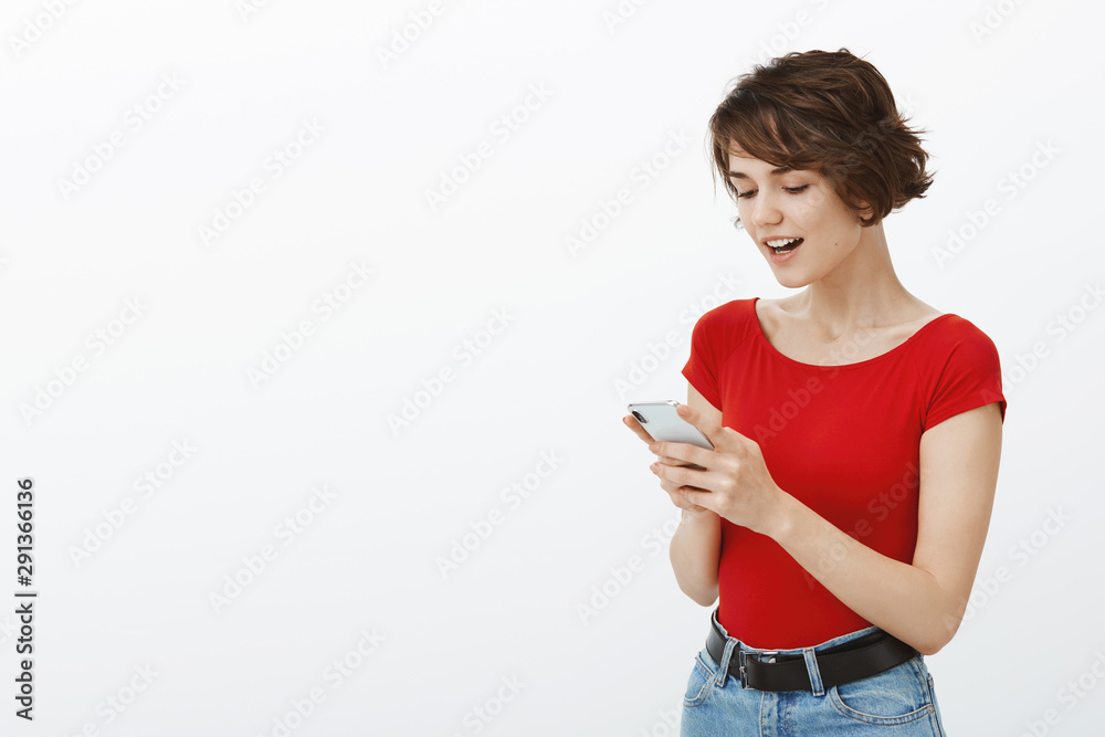 Amused excited good-looking woman short haircut hold sartphone read post open mouth look cellphone screen startled astonished amusing surprising message stand white background Amused excited good-looking woman short haircut hold sartphone read post open mouth look cellphone screen startled astonished amusing surprising message stand white background