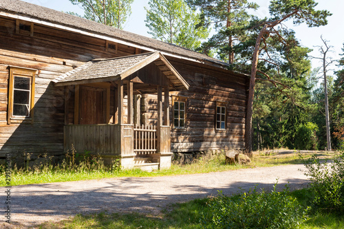 Old authentic wooden building of the 18-19th century, peasant traditional wooden hut near a road in a forest on the island of Seurasaari in Helsinki in Finland on a sunny summer day.