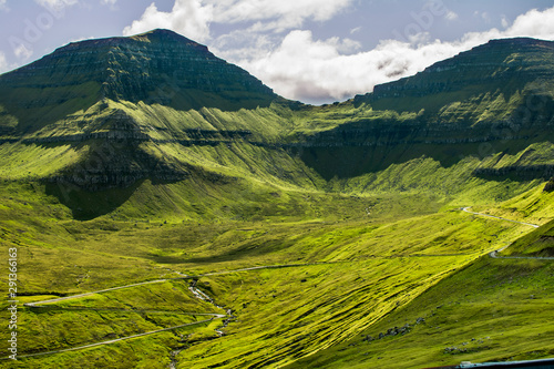 A road going up the monumental mountain with a green landscape (Faroe islands)