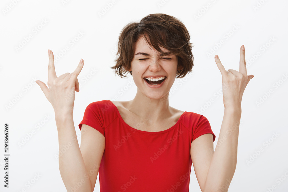 Daring carefree happy playful sassy woman short haircut having fun enjoying awesome fantastic party positive mood close eyes smiling broadly scream yeah show rock-n-toll heavy metal gesture Daring carefree happy playful sassy woman short haircut having fun enjoying awesome fantastic party positive mood close eyes smiling broadly scream yeah show rock-n-toll heavy metal gesture
