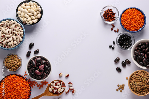 Red and brown lentils, black, brown and white beans are legumes that contain a lot of protein are located in bowls on white background, horizontal orientation, copy space