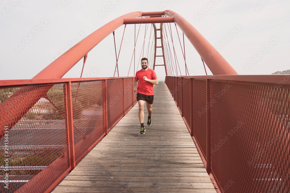 Running mid adult bearded man on bridge