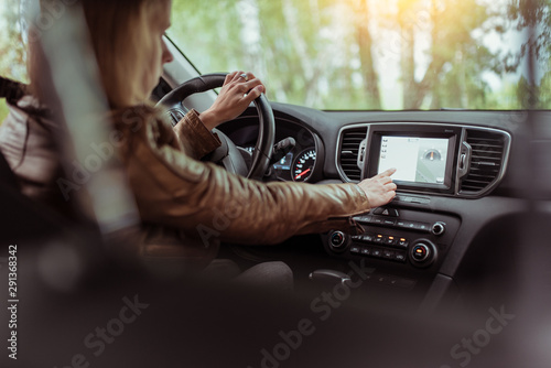 Woman girl in summer car interior in forest park, selects navigation touch screen, satellite internet application. Lost in search of a route, parking in the fresh air rest in the forest.