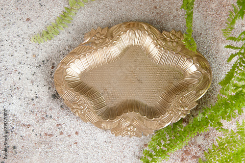 Old metal ashtray on concrete background.