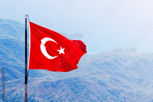 Red flag of Turkey with a star and a crescent on background of a sea mountain landscape.  photo