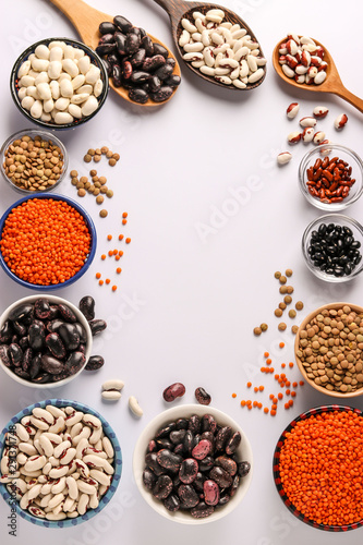 Red and brown lentils, black, brown and white beans are legumes that contain a lot of protein are located in bowls on white background, concept is healthy eating, copy space, vertical orientation