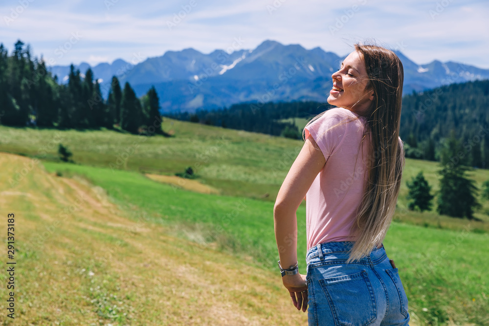 back view of girl with closed eyes and long hair on the meadow o