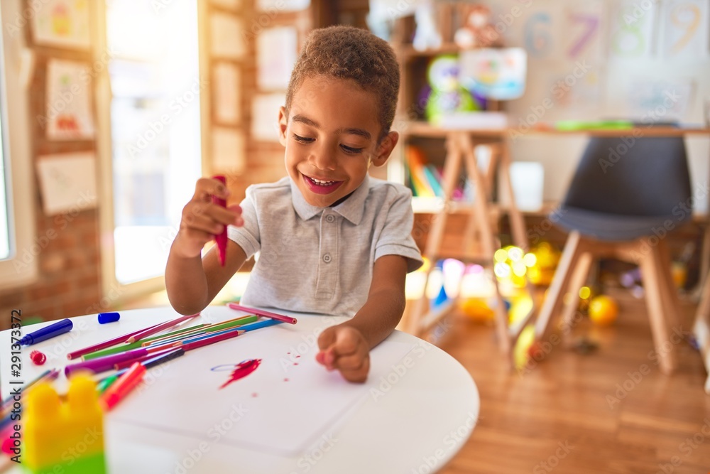 Beautiful african american toddler drawing using paper and marker pen smiling at kindergarten - obrazy, fototapety, plakaty 