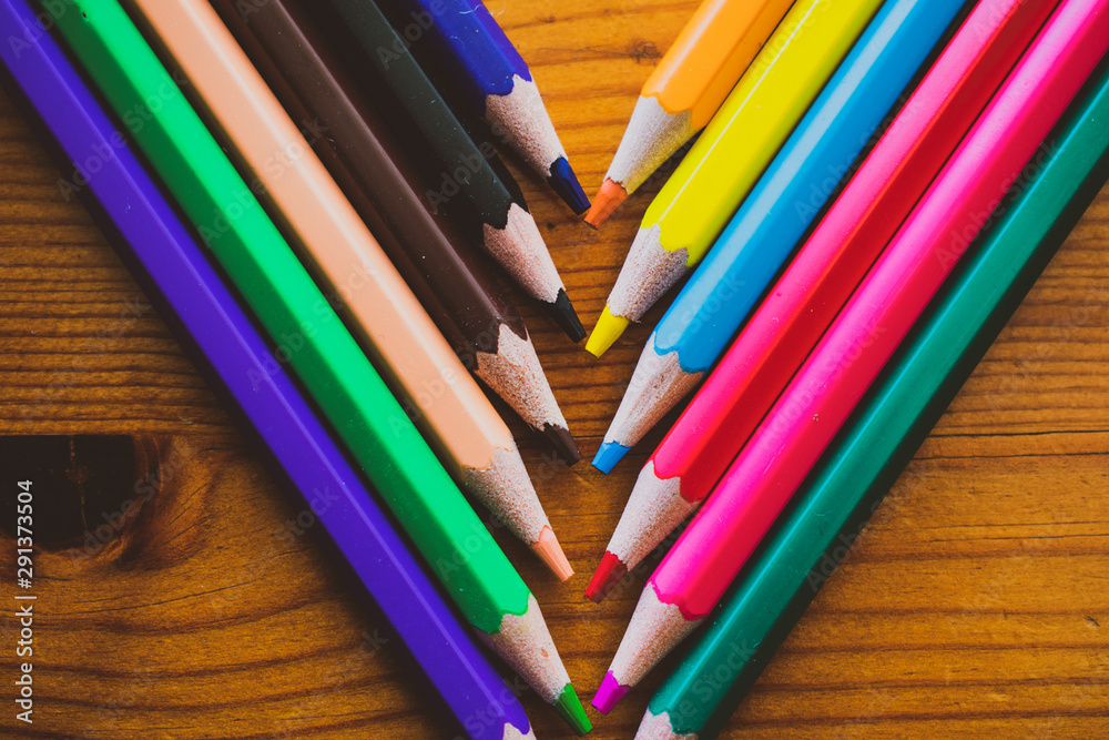Colors Sharpened Pencils in a diagonal row, close up isolated on a wooden background. Colors Sharpened Pencils in a diagonal row, close up isolated on a wooden background.