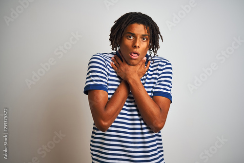 Afro man with dreadlocks wearing striped blue polo standing over isolated white background shouting suffocate because painful strangle. Health problem. Asphyxiate and suicide concept.