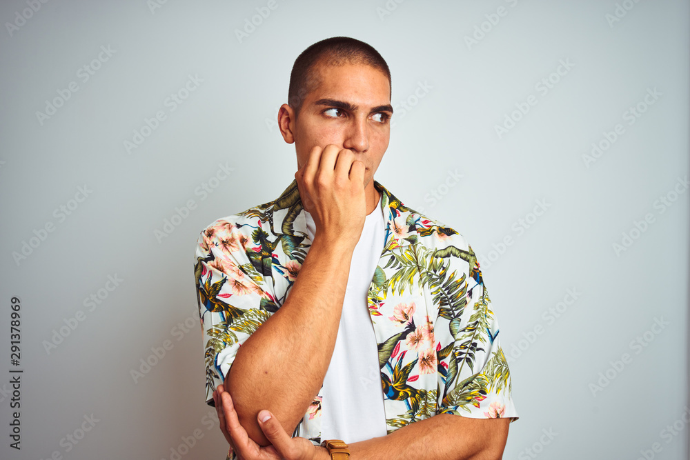 Young handsome man on holidays wearing Hawaiian shirt over white background looking stressed and nervous with hands on mouth biting nails. Anxiety problem. Young handsome man on holidays wearing Hawaiian shirt over white background looking stressed and nervous with hands on mouth biting nails. Anxiety problem.