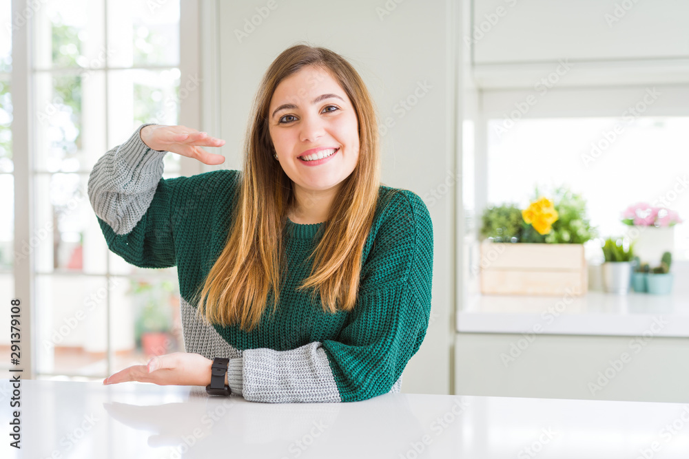 Young beautiful plus size woman wearing casual striped sweater gesturing with hands showing big and large size sign, measure symbol. Smiling looking at the camera. Measuring concept. Young beautiful plus size woman wearing casual striped sweater gesturing with hands showing big and large size sign, measure symbol. Smiling looking at the camera. Measuring concept.