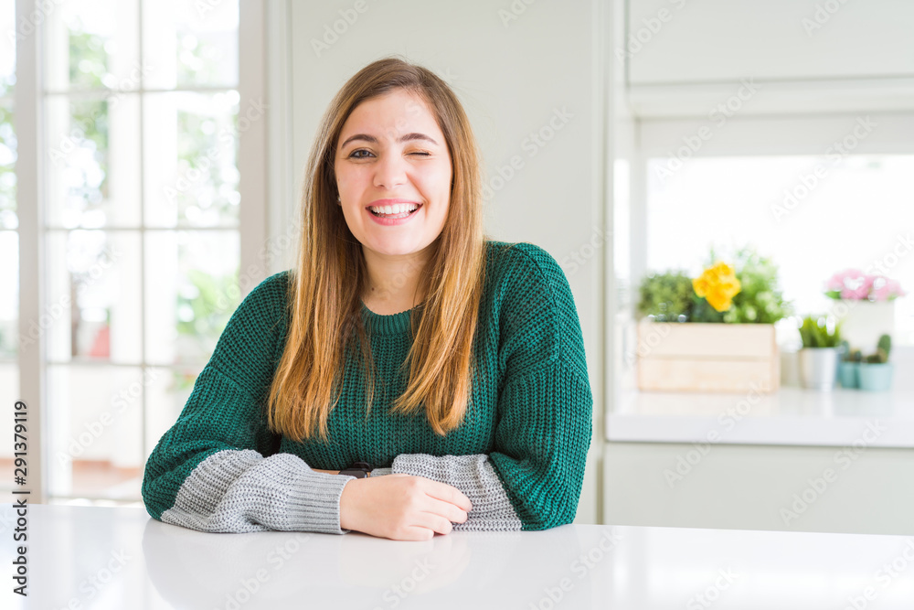Young beautiful plus size woman wearing casual striped sweater winking looking at the camera with sexy expression, cheerful and happy face. Young beautiful plus size woman wearing casual striped sweater winking looking at the camera with sexy expression, cheerful and happy face.