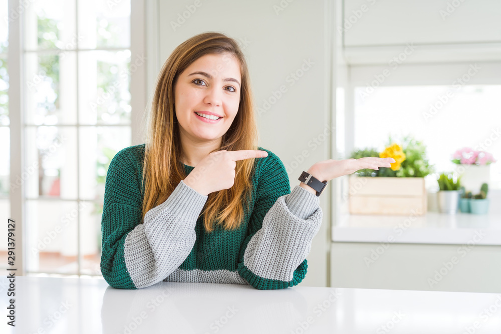 Young beautiful plus size woman wearing casual striped sweater amazed and smiling to the camera while presenting with hand and pointing with finger. Young beautiful plus size woman wearing casual striped sweater amazed and smiling to the camera while presenting with hand and pointing with finger.