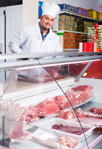 Smiling man near display with cooled meat